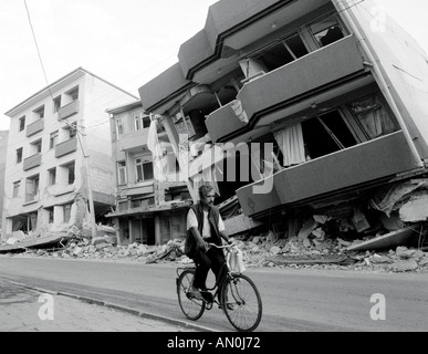 Man cycling past the remains of collapsed buildings soon after the 1999 earthquake in Izmit, near Istanbul, Turkey Stock Photo