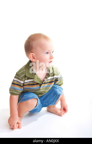 Young Boy White Background Setting Bent Down Holding Toes Looking off Camera with a Question in Mind Stock Photo
