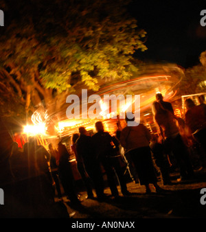 crowds watch a merry go round ride at a small town funfair for carnival week Stock Photo