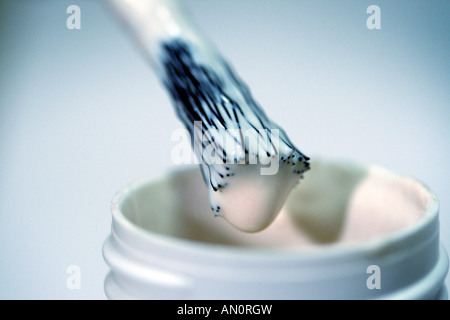 applicator brush dripping glue over pot of copydex glue Stock Photo