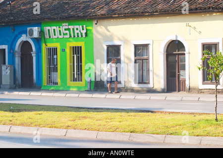 On the boulevard Ivana Cronjevica. Shops in small colourful houses. One shop with a sign saying 'New Industry'. A man walking past. Podgorica capital. Montenegro, Balkan, Europe. Stock Photo
