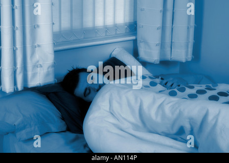 Man sleeping alone in bed at night Stock Photo