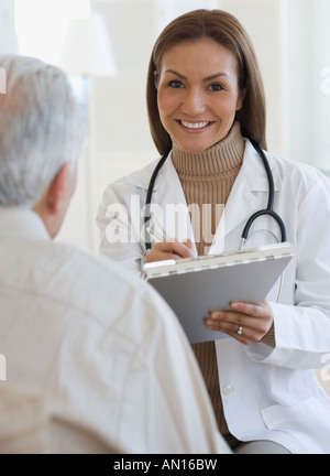 Portrait of Hispanic female doctor writing on chart Stock Photo