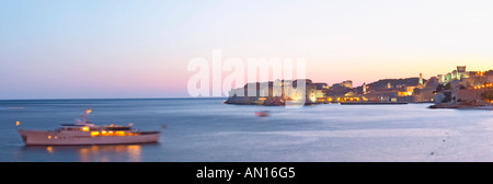 View over the Old Town in the evening after sunset, the city lights glimmering, the sky deep blue and orange pink, a luxury cruising ship moored in the bay, deep blue sea from the luxury Excelsior Hotel and Spa restaurant terrace Dubrovnik, old city. Dalmatian Coast, Croatia, Europe. Stock Photo