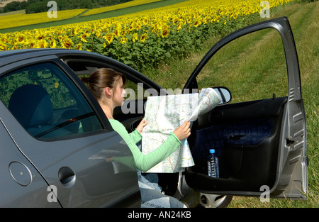 Young woman lost in the countryside in her car looking at a map Stock Photo