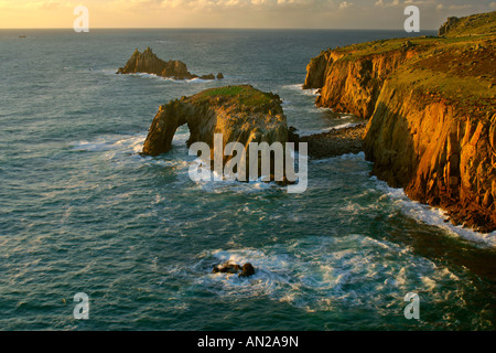 rugged coastline with rock arch in last evening light Lands End Cornwall England UK Stock Photo