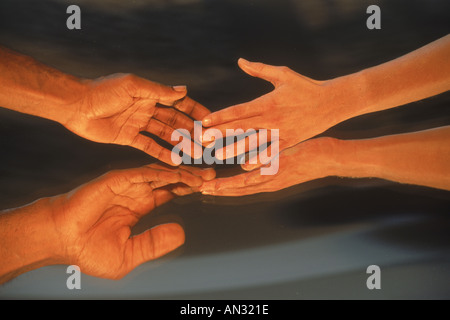 Two people reaching for each other across mirror Stock Photo