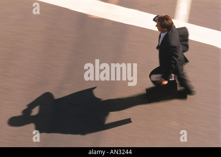 Businessman in crosswalk with cellphone and briefcase Stock Photo