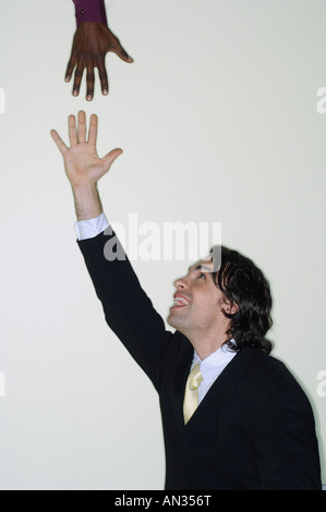 Businessman reaching up for hand Stock Photo