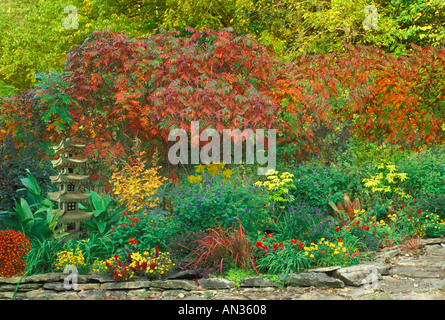 A colorful autumn flower garden with red Sumac trees and a tall Japanese lantern sculpture of a pagoda, Missouri USA Stock Photo
