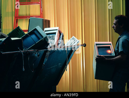 Latino workmen discarding obsolete computers in a dumpster Stock Photo