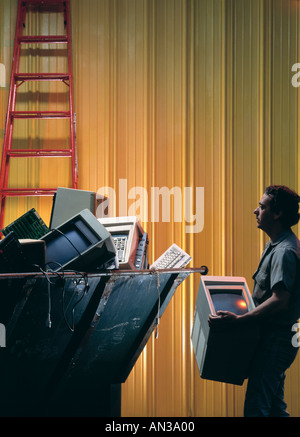 Latino workmen discarding obsolete computers in a dumpster Stock Photo