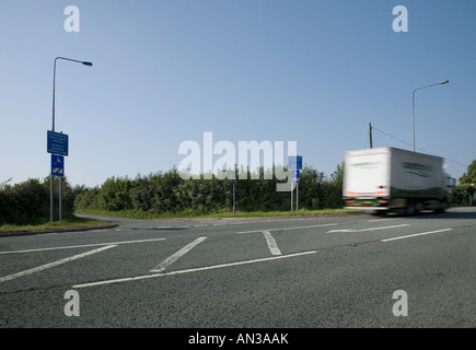 Satnav sign 'unsuitable for heavy goods vehicles' at a road junction with motion blurred truck passing by Stock Photo