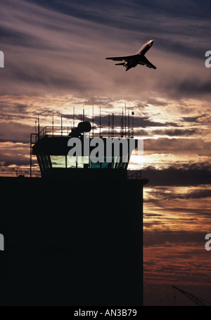 Plane taking off at sunset over control tower Stock Photo