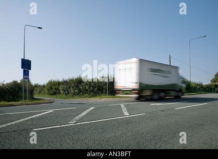 Satnav sign 'unsuitable for heavy goods vehicles' at a road junction with motion blurred truck passing by Stock Photo