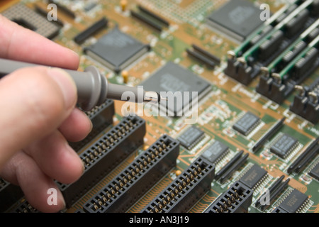 hand with probe testing electronic circuit board Stock Photo