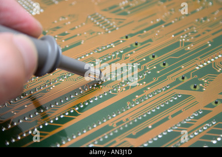 hand with probe testing electronic circuit board Stock Photo