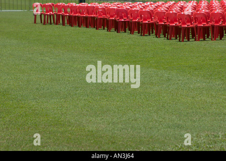 grass field with rows of red plastic chairs Stock Photo