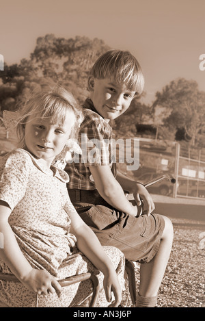 young boy rides off with a girl in the back of the old tricycle Stock Photo