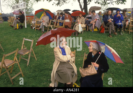 Chelsea Flower Show 1984 Meeting Point group of visitors waiting for friends. Two women sit under their umbrellas chatting 1980s UK HOMER SYKES Stock Photo