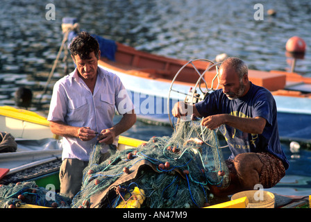 Two fishermen, Malta, Europe - mending nets in the harbour Stock Photo