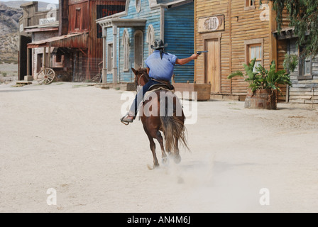 Cowboy on horseback riding away and shooting Stock Photo