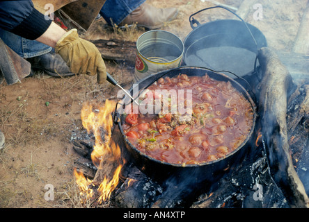 USA MONTANA Cowboys on a cattle drive in eastern Montana cook a bubbling chili stew over a campfire Stock Photo