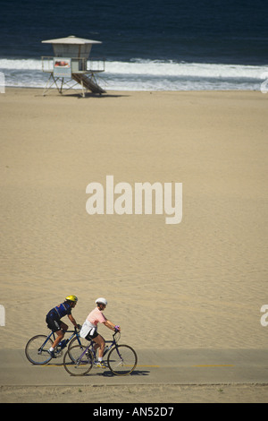 California Los Angeles couple riding bikes along path on beach at Playa Del Rey Stock Photo