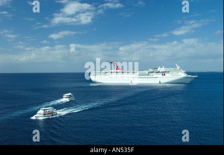 Carnival cruise ship Sensation with tender boat shuttling passengers between ship and shore at George Town, Grand Cayman Islands Stock Photo