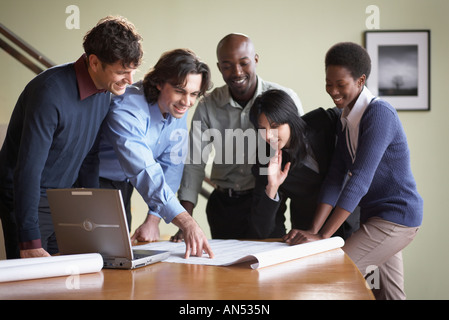 Multi-ethnic businesspeople looking at blueprints Stock Photo