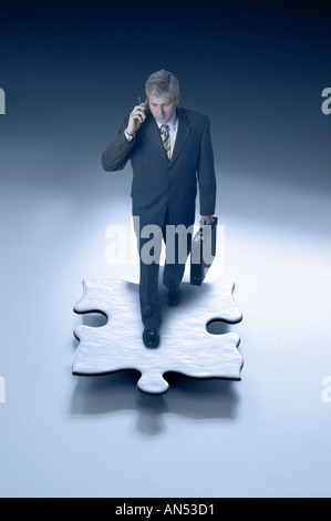 Businessman walking on a puzzle piece Stock Photo