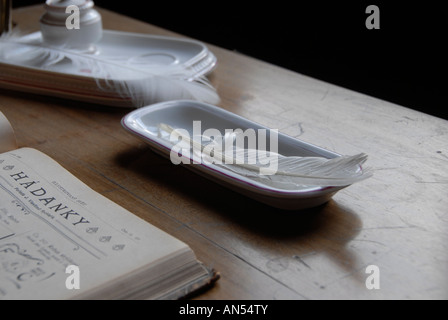 Vintage writing materials including a feather quill  and a white ink pot on a wooden desk Czech republic Stock Photo