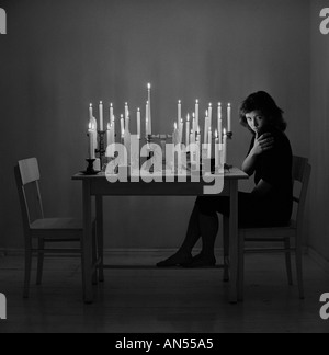 Sad woman sitting in empty room Several lit candles on table. 18, 19, 20, 20s, 20-24. 25-29, 30s years old, Stock Photo