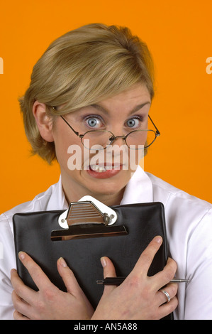 BLOND FEMALE NURSE WITH WHITE COAT AND CLIP BOARD SHOWING EXPRESSION OF DOUBT Stock Photo