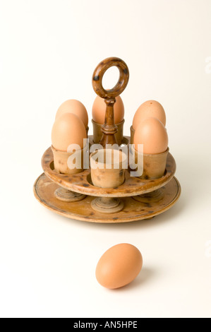 five eggs in an old fashioned  wooden egg holder with one by itself in front on white background Stock Photo