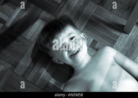 Small boy making a funny face for camera smiling and playing Cyan Toned  black and white