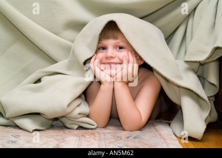 Smiling boy playing under blanket playful children Stock Photo