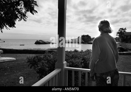 Woman looks off of her porch on Money Island off the coast of Connecticut Stock Photo