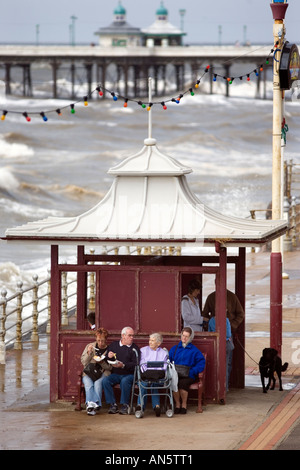 Visitors to Blackpool UK sit by a shelter on the seafront on an August Bank holiday Stock Photo