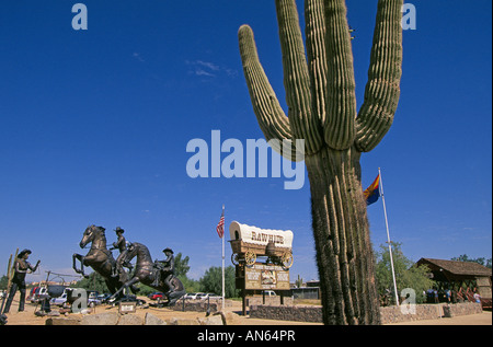 A giant saguaro cactus from the sonoran desert and sculptures of cowboys at Rawhide a large Phoenix theme park Stock Photo