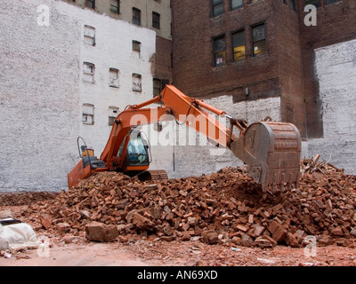 Backhoe moving bricks from demolished building on Manhattan real estate Stock Photo