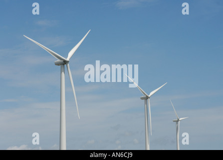Three wind turbines, close-up of blades, against blue sky. Wind power "wind farm" turbines alternative energy, renwable energy. Stock Photo