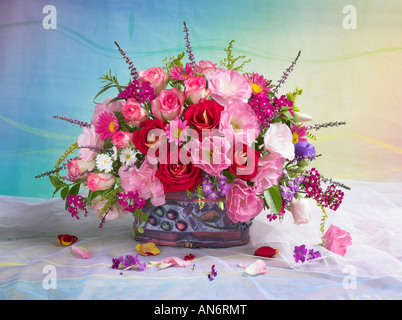 Studio arranged colorful bunch bouquet of red roses and pink anemones in a basket on a pastel background Stock Photo