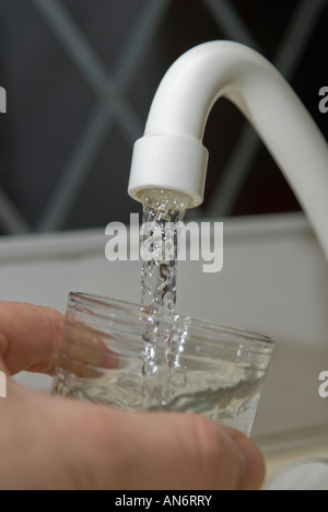 Filling a glass with water from kitchen tap with a hand holding the glass Stock Photo