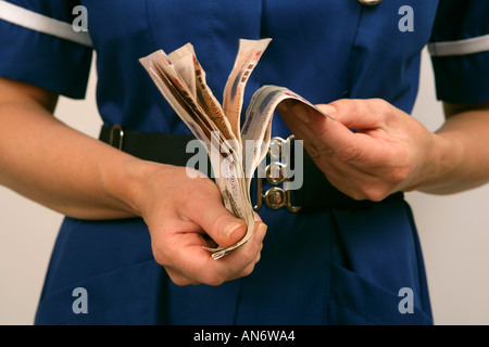 Nurse wearing blue uniform counting her money Stock Photo