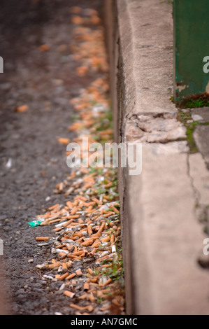 CIGARETTE STUBS LYING IN THE GUTTER IN AN URBAN LOCATION UK Stock Photo