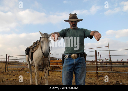 An Israeli cattle rancher wearing a pistol in a farmyard in the Golan heights northern Israel Stock Photo