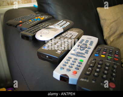Remote controls arranged on the arm of a sofa Stock Photo