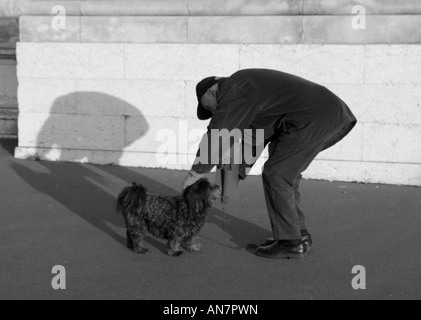 Elderly man tending to his dog on Pont Alexandre III Paris France Stock Photo