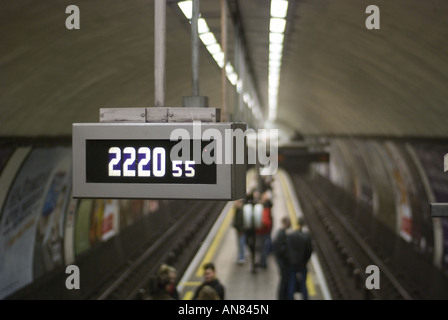 A clock hanging from the ceiling shows the time of 22:20, or 10:20pm, at the Clapham Common underground station in London. Stock Photo